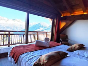 A bedroom with a bed, pillows, a towel, and a view of mountains through large windows. - The Three Massifs, 12 people, view of Mont Blanc, and close to the slopes (Saint-Gervais-les-Bains)