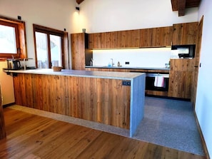 Eine Küche mit Holzschränken, einer zentralen Kochinsel und einem eingebauten Backofen.