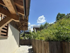 A wooden staircase leading to a building with a sloped roof, surrounded by greenery and a clear sky. - The Three Massifs, 12 people, view of Mont Blanc, and close to the slopes (Saint-Gervais-les-Bains)