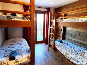 Ein Zimmer mit Etagenbetten, einer Holzleiter und Blick durch eine Tür.