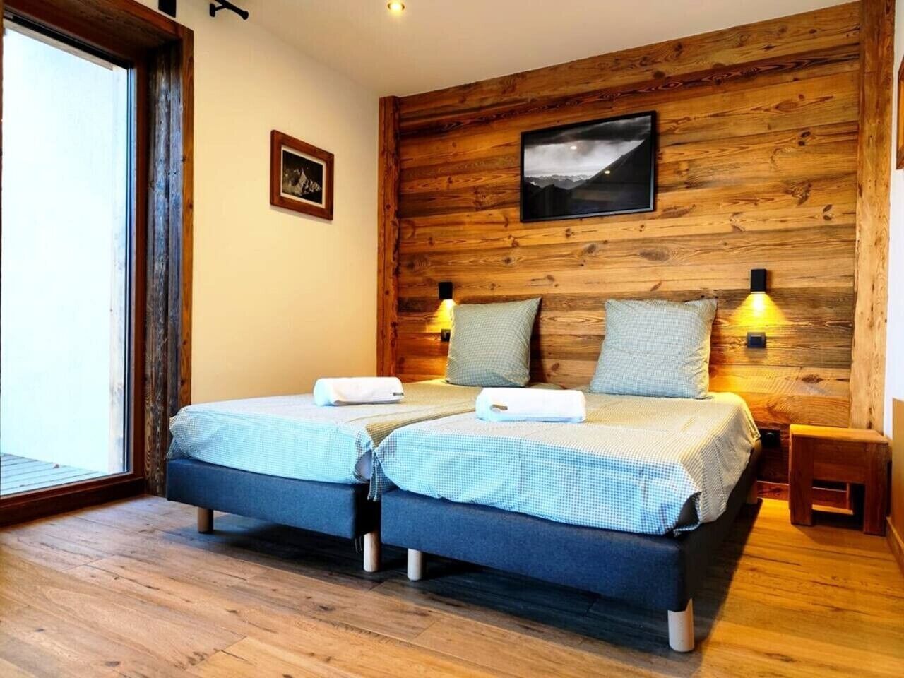 Habitación doble con dos camas, paneles de madera en las paredes, un cuadro enmarcado y una ventana.
