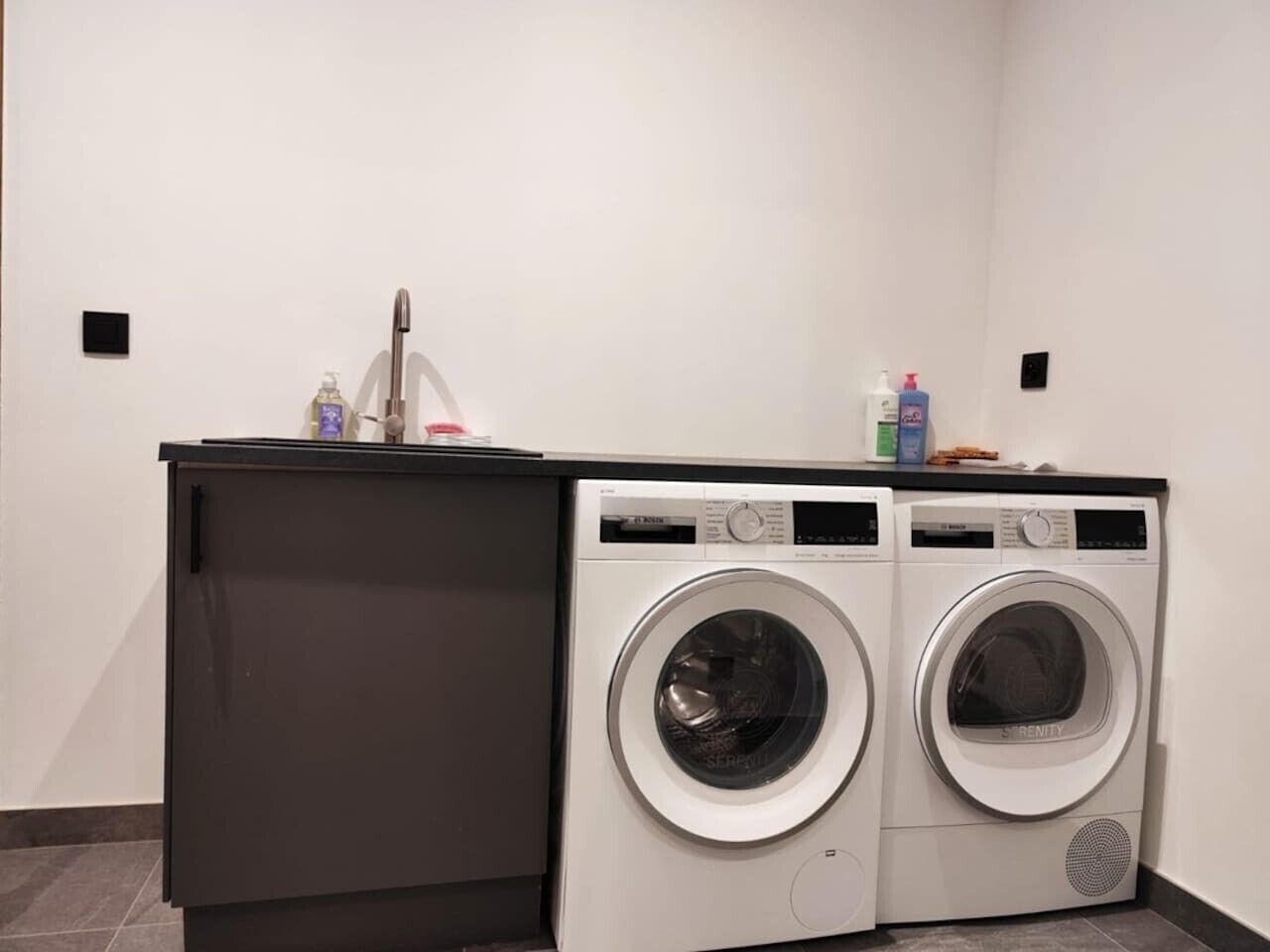 Ein Waschbereich mit zwei Waschmaschinen und einem dunklen Schrank.