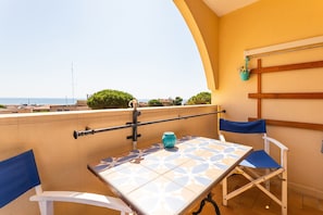 A balcony with a table and chairs, a view of the sea, and a hanging basket with utensils. - Chez MarieDo - Bel appt pour 2 avec balcon vue mer (Fleury)