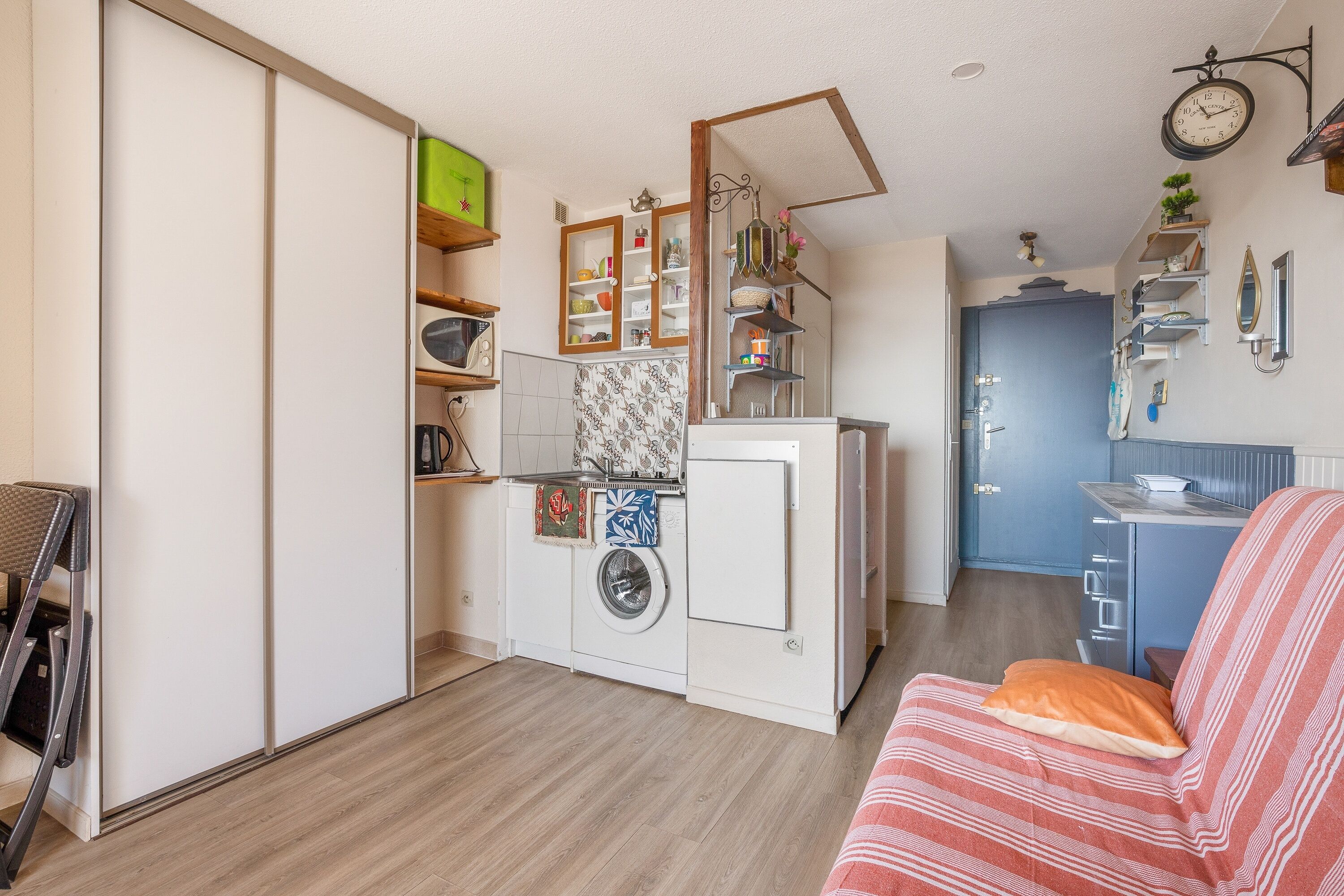 A compact living space with a kitchenette, a washing machine, and a dining area.