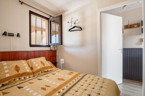 A bedroom with a bed, a mirror, a hanging light fixture, and a door leading to another room. - Chez MarieDo - Bel appt pour 2 avec balcon vue mer (Fleury)