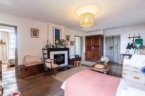 Ein Zimmer mit Kamin, Holmöbeln, einem Bett mit sterngestrom Aufhängung.