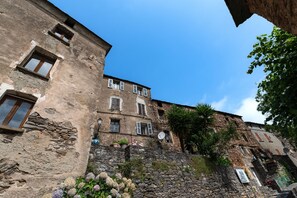 Ein historisches Steinhaus mit zahlreichen Fenstern und einer Steintreppe, die zum Eingang führt.