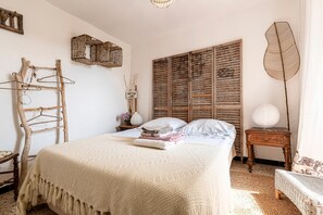 A bedroom with a bed, a wooden wardrobe, a hanging chair, and a bedside table with a lamp. - Tribbiolu - Cocon corse typique (San-Giovanni-di-Moriani)