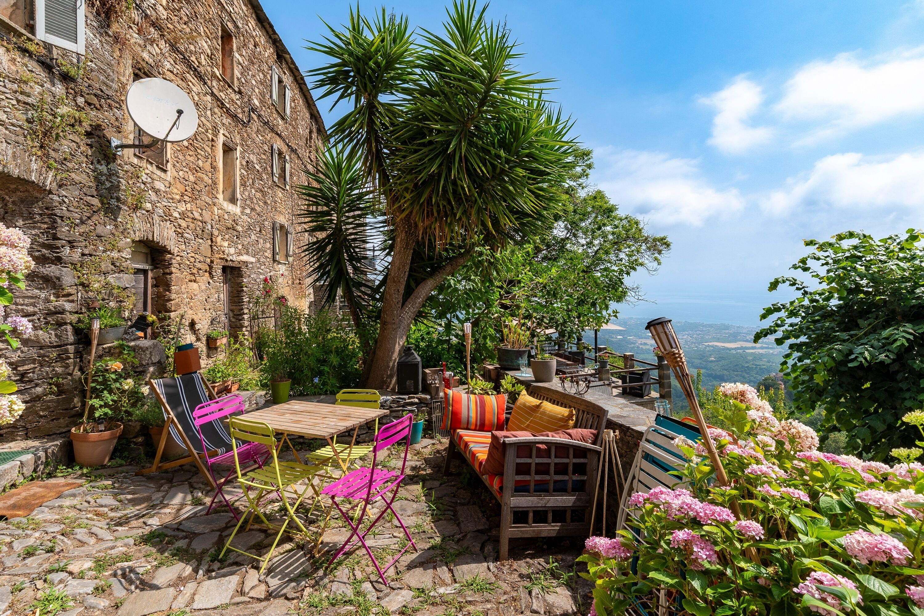 A rustic stone building with a patio area featuring outdoor furniture and potted plants.