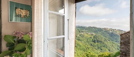 A room with a window overlooking a mountainous landscape.