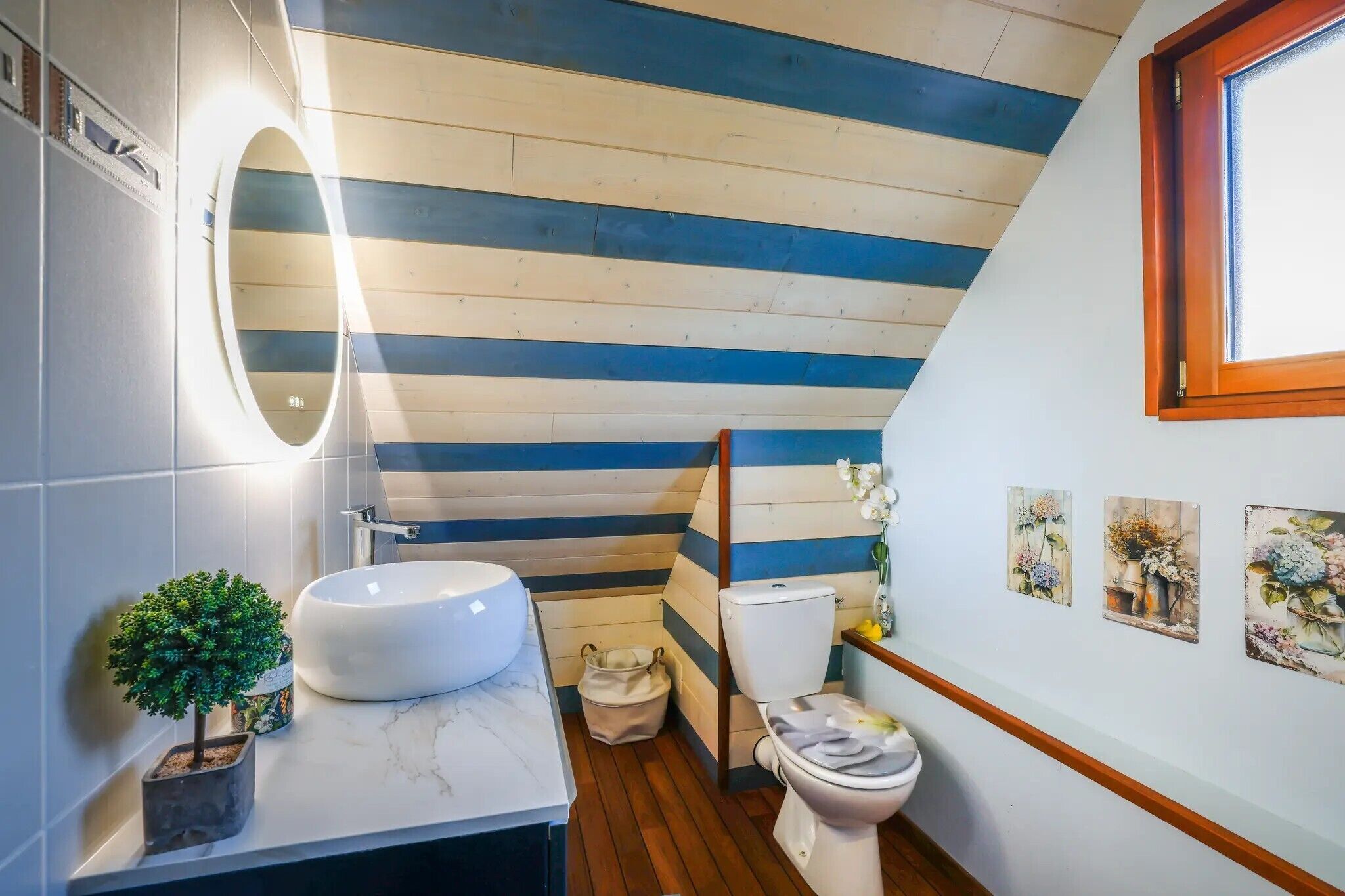 Une petite salle de bain avec un lavabo blanc, des toilettes et une petite plante en pot.