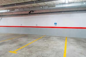 A parking garage with numbered parking spaces and a red stripe. - Cubo's Bel-Air Estepona Apartment / communal pool / parking included / air conditioning / free Wi-Fi (Estepona)