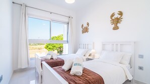 Een hotelkamer met twee bedden, een groot raam en uitzicht op groen.