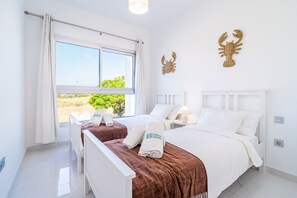 A hotel room with two beds, a large window, and a view of greenery outside. - Cubo's Bel-Air Estepona Apartment / communal pool / parking included / air conditioning / free Wi-Fi (Estepona)