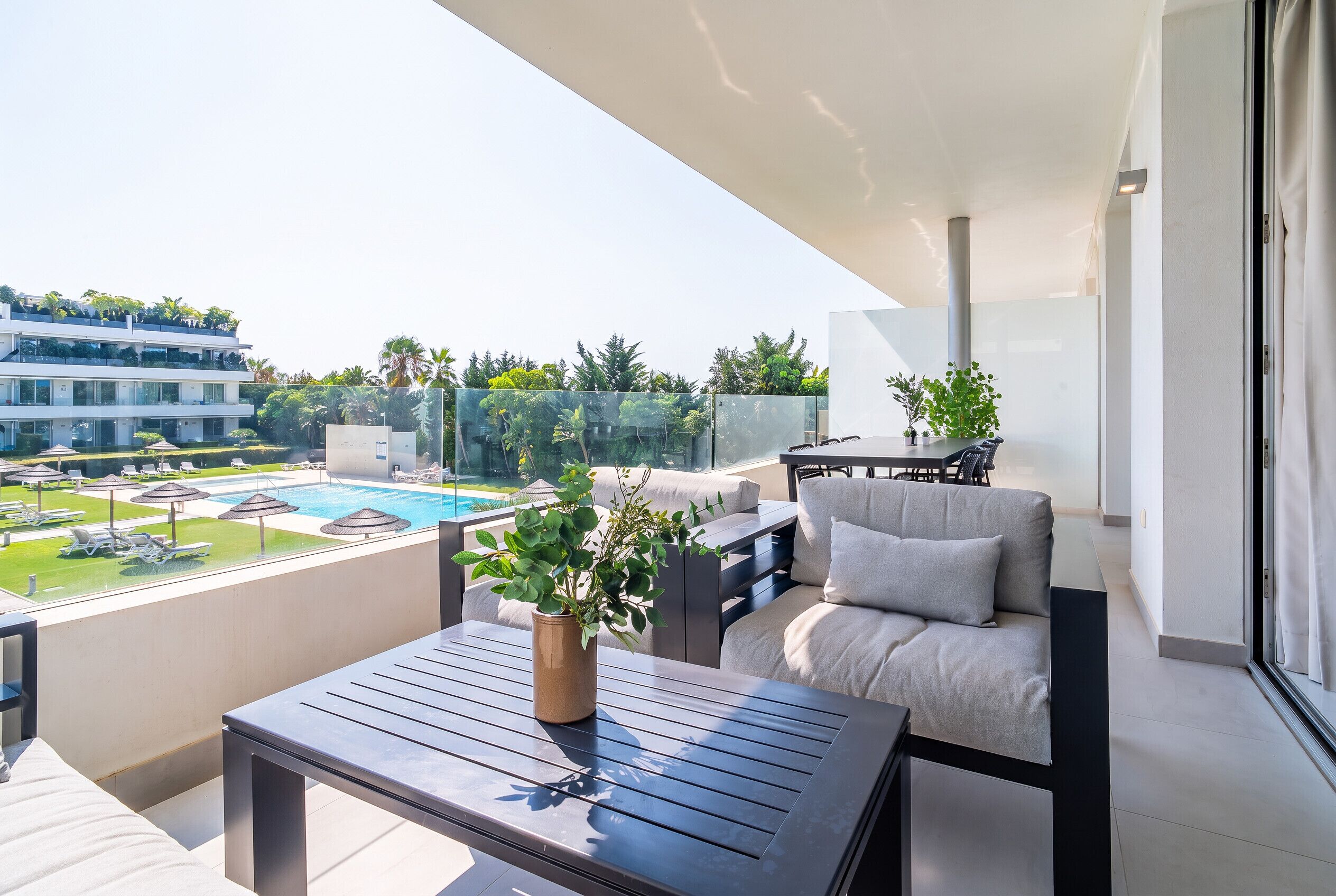 A balcony with a pool view, outdoor furniture, and a potted plant.