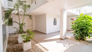 Een modern interieur met glazen dak, witte muren en potplanten.