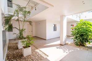 A modern interior with a glass ceiling, white walls, and potted plants. - Cubo's Bel-Air Estepona Apartment / communal pool / parking included / air conditioning / free Wi-Fi (Estepona)