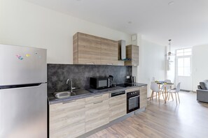 A modern kitchen with a built-in microwave, a sink, and a dishwasher. - Le Cocon Bleu - Bel appt pour 6 en centre-ville (Montlucon)