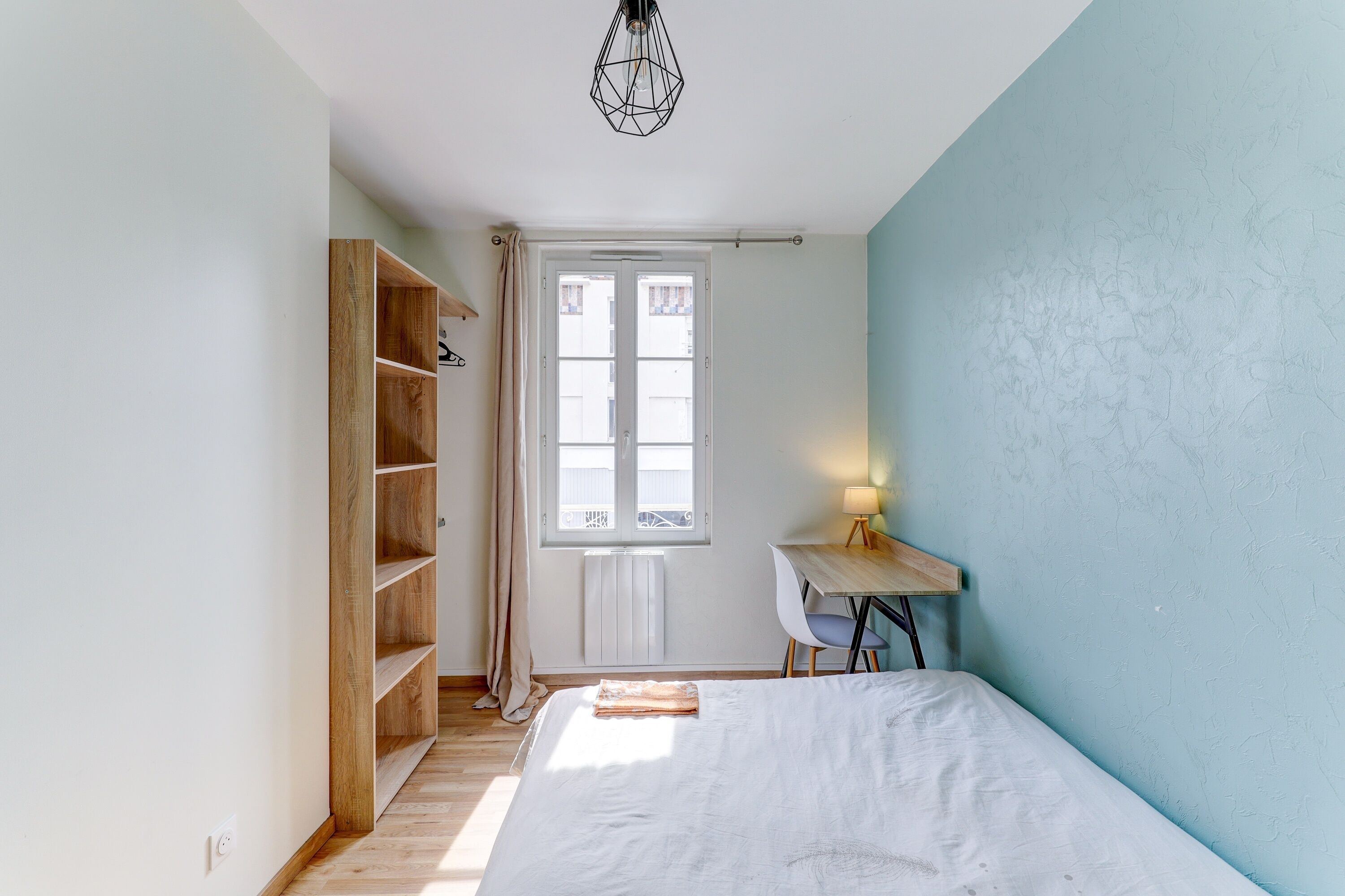 Une chambre à coucher avec un lit, un bureau, une armoire et une fenêtre.