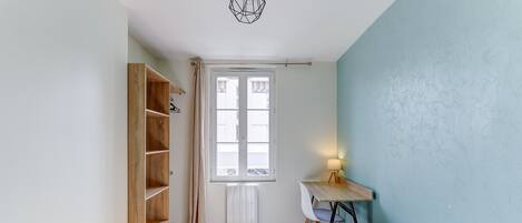 Une chambre à coucher avec un lit, un bureau, une armoire et une fenêtre.