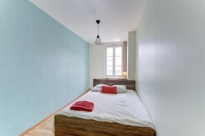 Ein Schlafzimmer mit Bett, Fenster und einer Pendelleuchte.