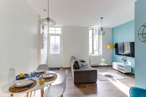 Ein modernes Wohnzimmer mit einer Couch, einem Esstisch und einem an der Wand montierten Fernseher.
