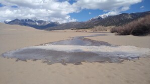 A desert landscape with a riverbed leading to mountains. - 5 acre campground in Blanca perfect for outdoor getaways with picturesque view (Blanca)