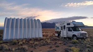 A white RV parked in a desert with mountains in the background. - 5 acre campground in Blanca perfect for outdoor getaways with picturesque view (Blanca)