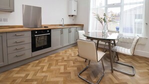 Una cocina moderna con horno empotrado, campana extractora de acero inoxidable y ventana con vista a edificios.