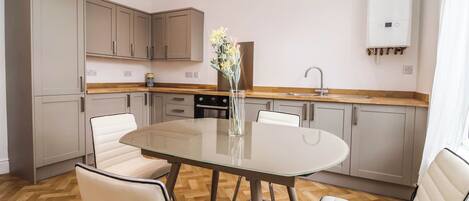 Une cuisine moderne avec un îlot central, des chaises blanches et un vase de fleurs.