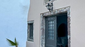 Um edifício com parede de pedra, uma porta e uma pequena palmeira.