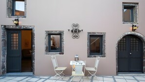 Fachada de um edifício com duas portas, duas janelas e uma pequena mesa com cadeiras.