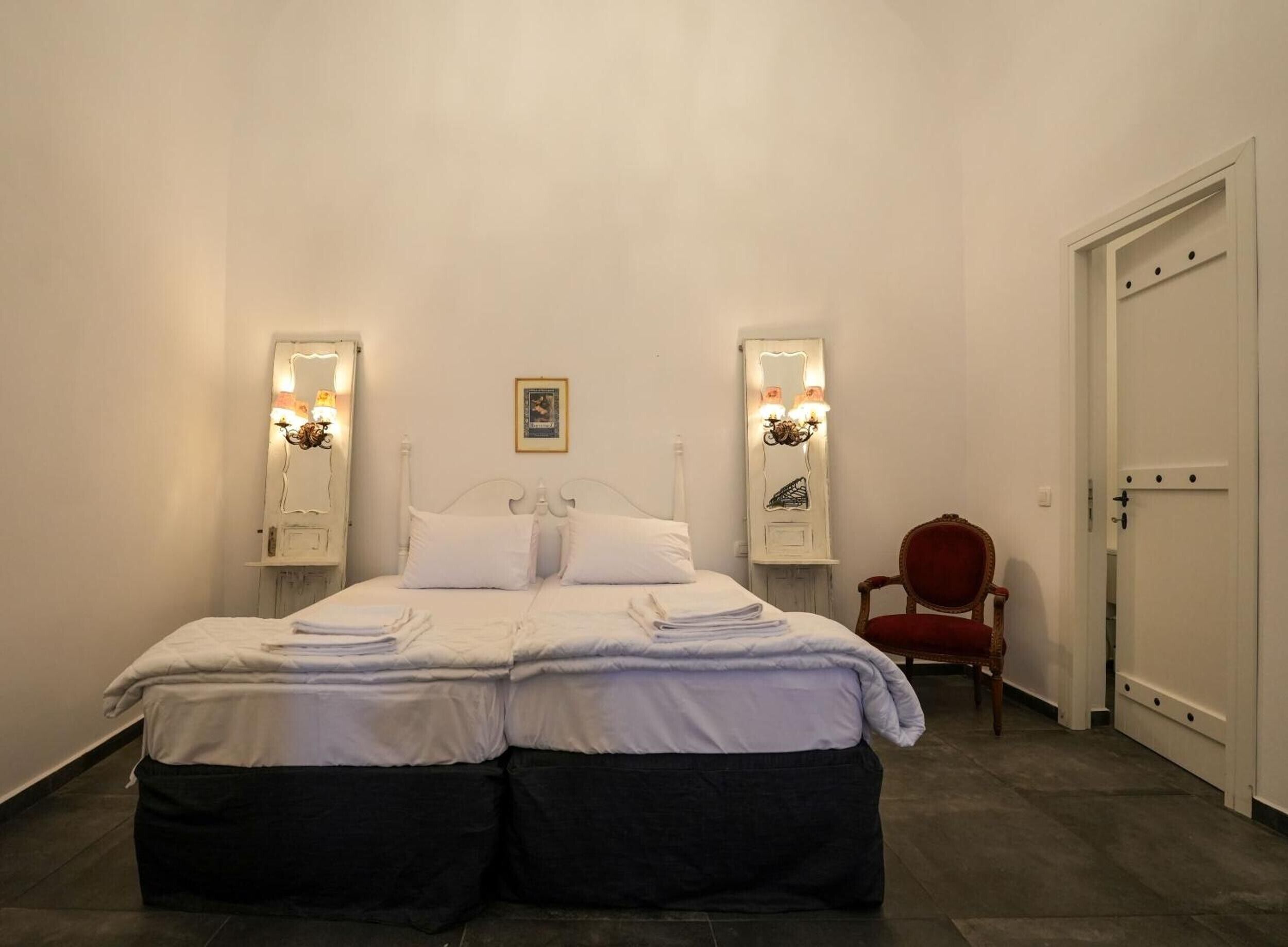 A bedroom with a bed, two bedside tables with lamps, a chair, and a door.