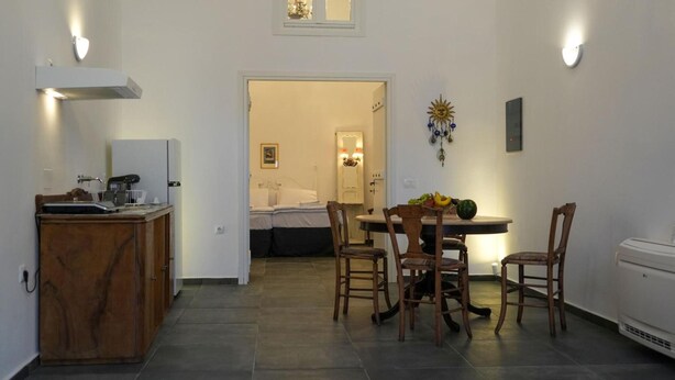 A compact kitchen with a dining area, a small table, and chairs. There is a window above the sink and a wall-mounted light fixture. - Apartment 'Two-Bedroom' with Wi-Fi and Air Conditioning (Emporio)