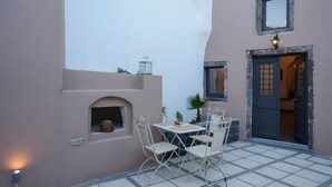 A patio with a table and chairs, a small shelf with a pot, and a door leading to an interior space. - Apartment 'Two-Bedroom' with Wi-Fi and Air Conditioning (Emporio)