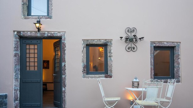 Un bâtiment doté d’une porte, de deux fenêtres, d’un luminaire fixé au mur et d’une table avec des chaises.