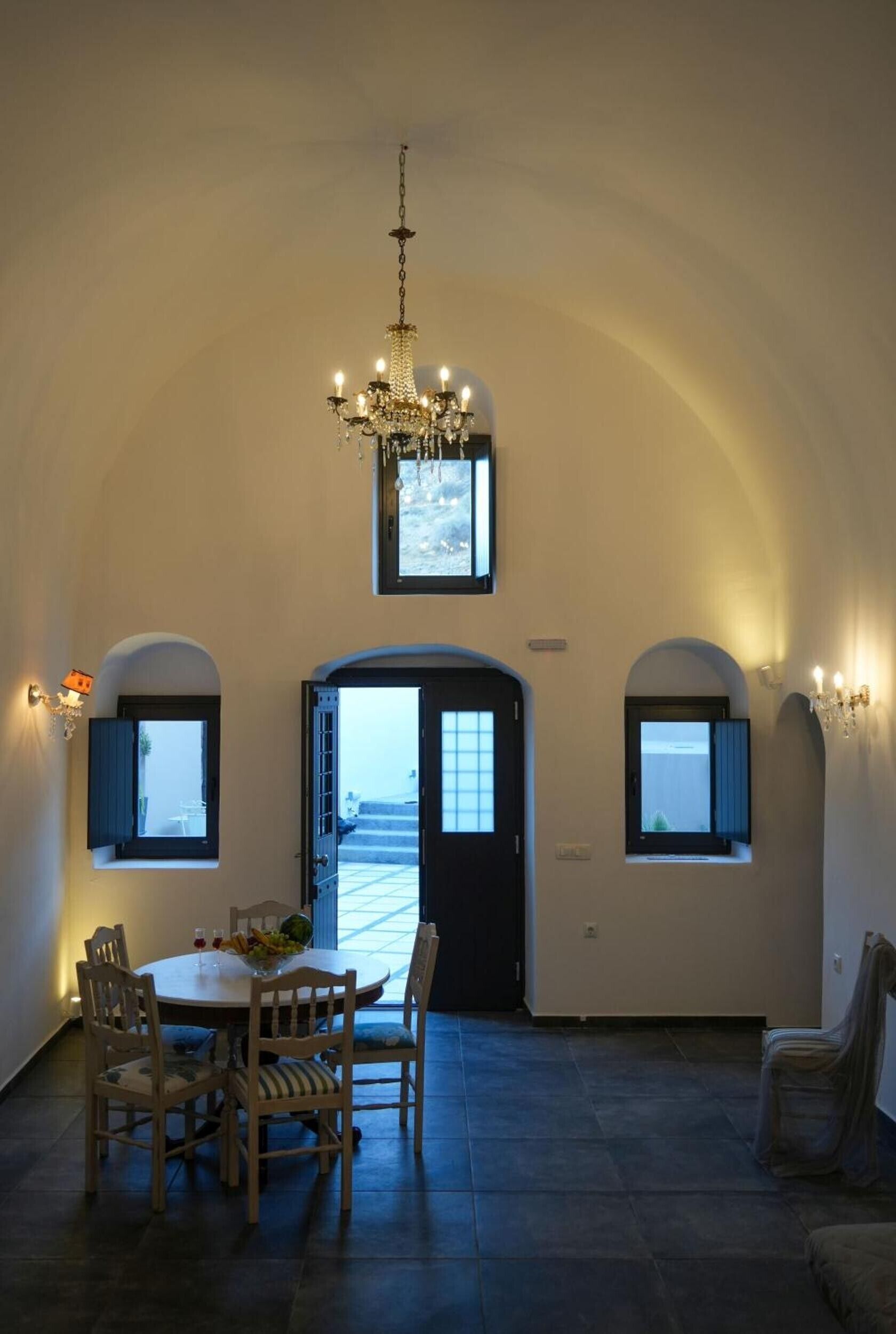Ein Essbereich mit einer Chandelierleuchtre, einem Tisch mit Stühlen und Blick durch eine offene Tür.