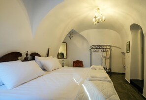 Slaapkamer met een groot bed, nachtkastje, hanglamp en inloopkast met kleren.