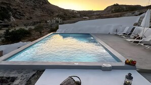 Une piscine avec des chaises longues et une table agrémentée d’une lanterne et d’un panier.