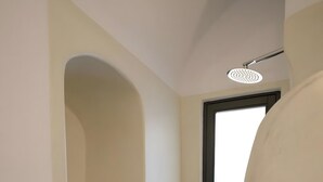Un couloir étroit avec une petite alcôve abritant une étagère où sont rangés les articles de toilette.