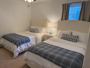 A hotel room with two beds, each with a headboard, a bedside table with a lamp, and a window with curtains. - Entire House a mile walk to Jordan-Hare Stadium and Downtown Auburn (Auburn)