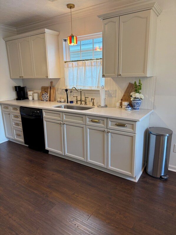 A kitchen with white cabinetry, a stainless steel sink, a dishwasher, and a trash can. - Entire House a mile walk to Jordan-Hare Stadium and Downtown Auburn (Auburn)