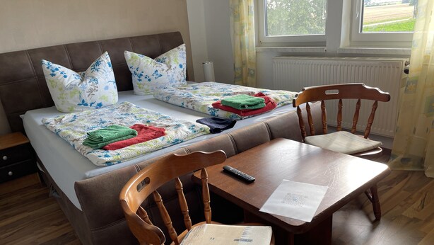 Une chambre à coucher avec un lit, deux oreillers, une table de chevet, une chaise et une fenêtre.