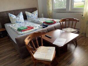 Une chambre à coucher avec un lit, deux oreillers, une table de chevet, une chaise et une fenêtre.