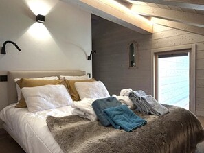 A bed with a white and beige headboard, a fur throw, and folded towels. - Alpa Cabin (12 People) View of Mont Blanc & Jacuzzi (Saint-Gervais-les-Bains)