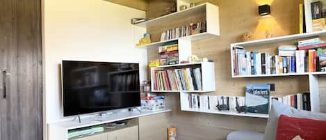 Una sala de estar moderna con un televisor de pantalla plana, estanterías empotradas, un sofá gris y una mesa de centro de madera.