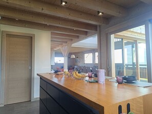 A kitchen with a wooden countertop, a sliding door, and a view through large windows. - Alpa Cabin (12 People) View of Mont Blanc & Jacuzzi (Saint-Gervais-les-Bains)