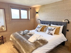 A bedroom with a large bed, wooden walls, a window, and a wall-mounted light fixture. - Alpa Cabin (12 People) View of Mont Blanc & Jacuzzi (Saint-Gervais-les-Bains)