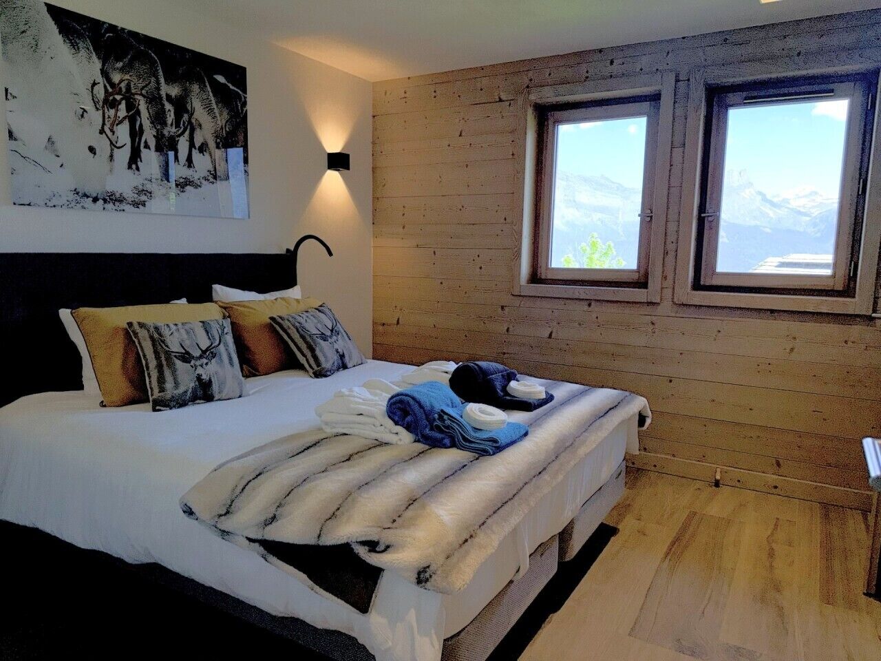 Un dormitorio con cama, almohadas, una colcha y un cuadro en la pared.