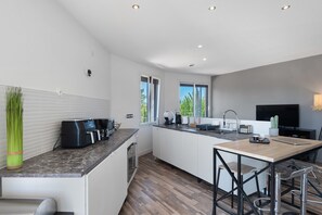 A modern kitchen with a built-in island, a coffee machine, and a TV.